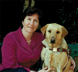 Maribel in a purple shirt sitting with her guide dog Nev