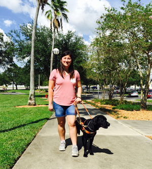 Michelle walking down campus sidewalk with dog guide