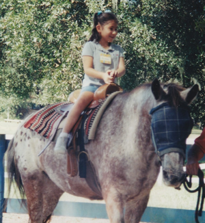 A young Michelle sitting atop a horse