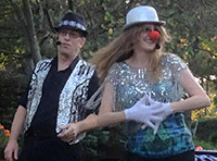 Melissa in a glittery hat and clown nose with her husband Larry in a sparkling vest performing their comedy show.