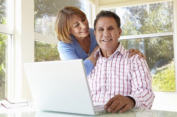 Senior Hispanic couple in home office with laptop