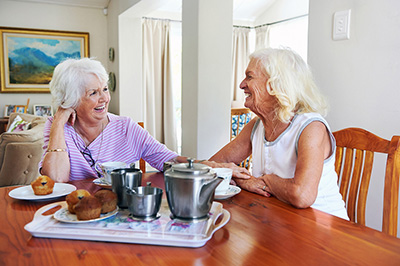 Two retired older women sitting at a table laughing 
