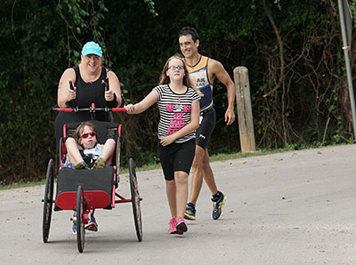 Erin Bowdoin running in a triathlon pushing her son JD who has CHARGE Syndrome in a stroller