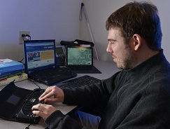 A man in an office uses a braille note taker 