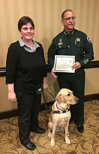 Alexis Read with her guide dog looking at the camera at a graduation ceremony