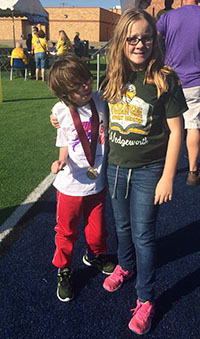 JD wearing his gold medal standing with his twin sister