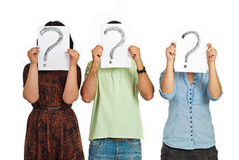 Three casual people standing in a line and holding question markets isolated on white background