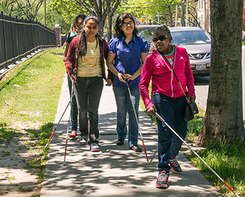 Young women walking with canes on the sidewalk