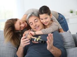 Woman with daughter hugging a grandfather and giving him a present