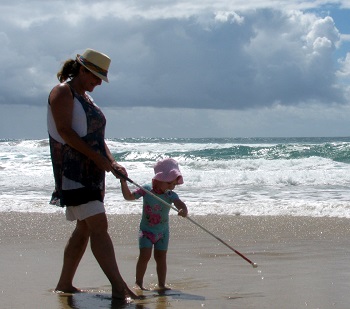 woman using cane walking on beach with young granddaughter