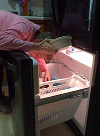 Mary looking in her freezer holding a white ceramic dish