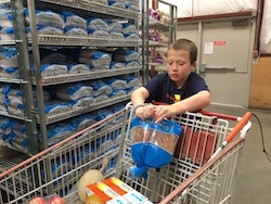 Eddie holding a bag of rolls while leaning on a grocery cart