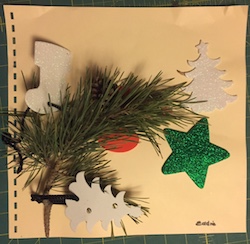 A collection of cut outs in different shapes and an evergreen branch on braille paper