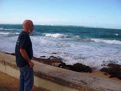 Man standing on the beach looking out into the ocean as the waves come crashing in