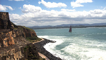 Landscape of a rocky beach with boat off in the distance sailing away