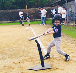 Jake at bat hitting a ball during a tee ball game