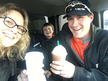 Emily Coleman sitting in the car with her husband and son, Eddie, smiling at the camera