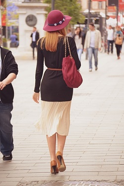 woman walking on street with back to camera, handbag hanging at side