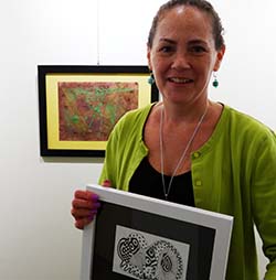 Artist holding a piece of artwork in a gallery