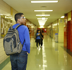 Student walking down a school hallway with his back to the camera