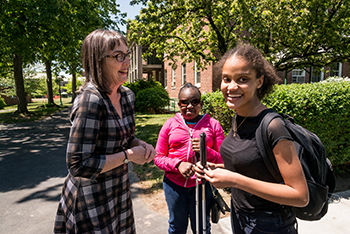 A woman standing outside with two female students laughing