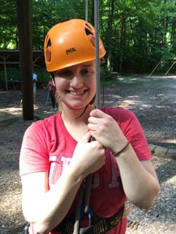 A camper in rock climbing gear smiling at the camera