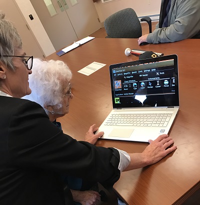 older woman using laptop to learn zoomtext with instructor looking over shoulder