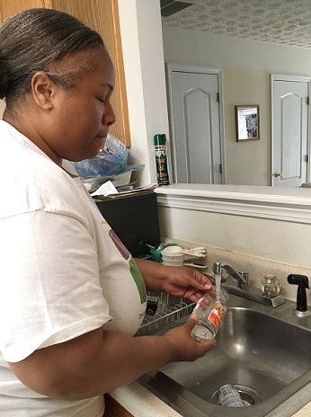 woman washing bottle in sink