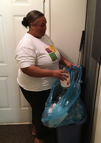 woman putting bottle in blue recycle bag