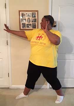 A side view of Empish demonstrating a self-defense stance with her feet apart and her hands up near her shoulders