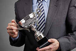 Close up of a man in a suit holding a silver award