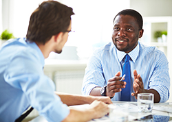 Two businessmen talking, one facing the camera and the other one facing away from the camera