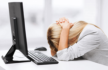 A woman with her head down on the desk in front of a computer