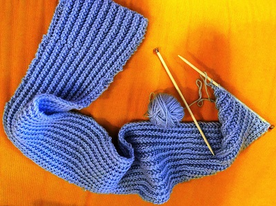 blue knitted scarf on a table with bamboo knitting needles
