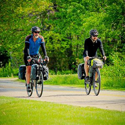 Two bike riders from Shared Vision Quest riding on a paved road