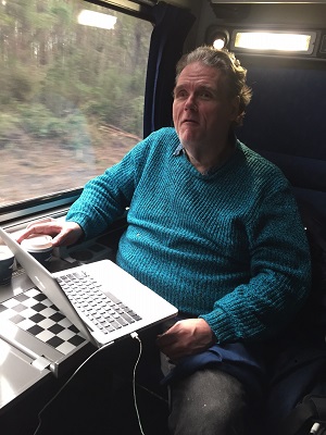 man sitting on train with laptop open