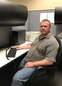 John Carty sitting at his desk, facing the camera