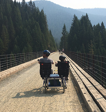 Eddie and his dad riding on a bike on the Hiawatha trail on the Montana/Idaho border with their backs to the camera