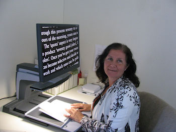 Maribel using a video magnifier, looking back at the camera