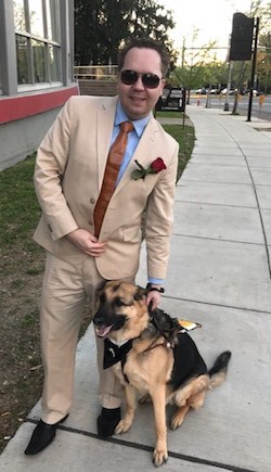 James Boehm standing on the sidewalk with his guide dog