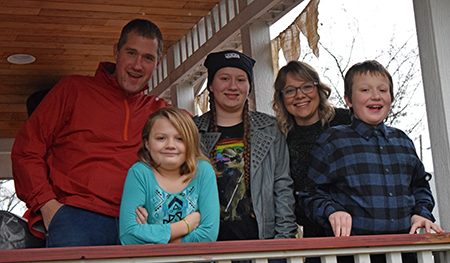 Emily Coleman with her husband and their three children, standing outside on a porch