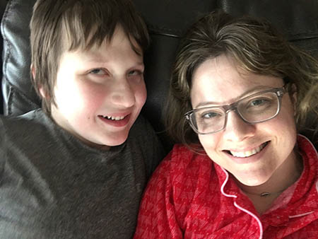 Emily Coleman and her son Eddie laying down together looking up and smiling at the camera