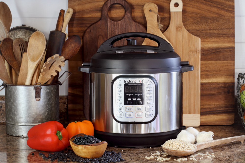 Instant Pot surrounded by various kitchen tools, cutting board