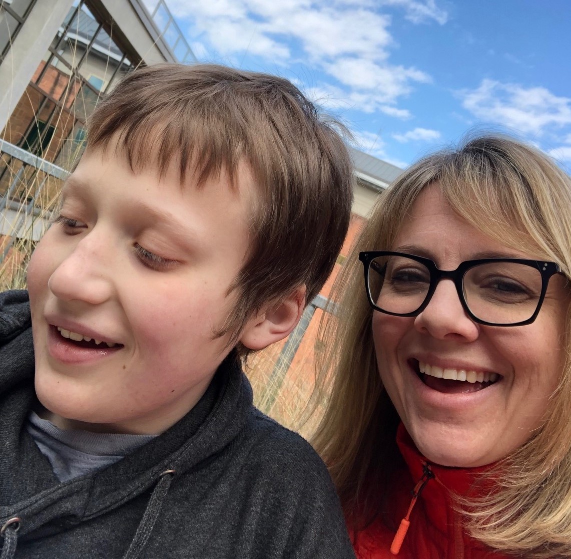 Blonde woman in glasses smiling with teenage son