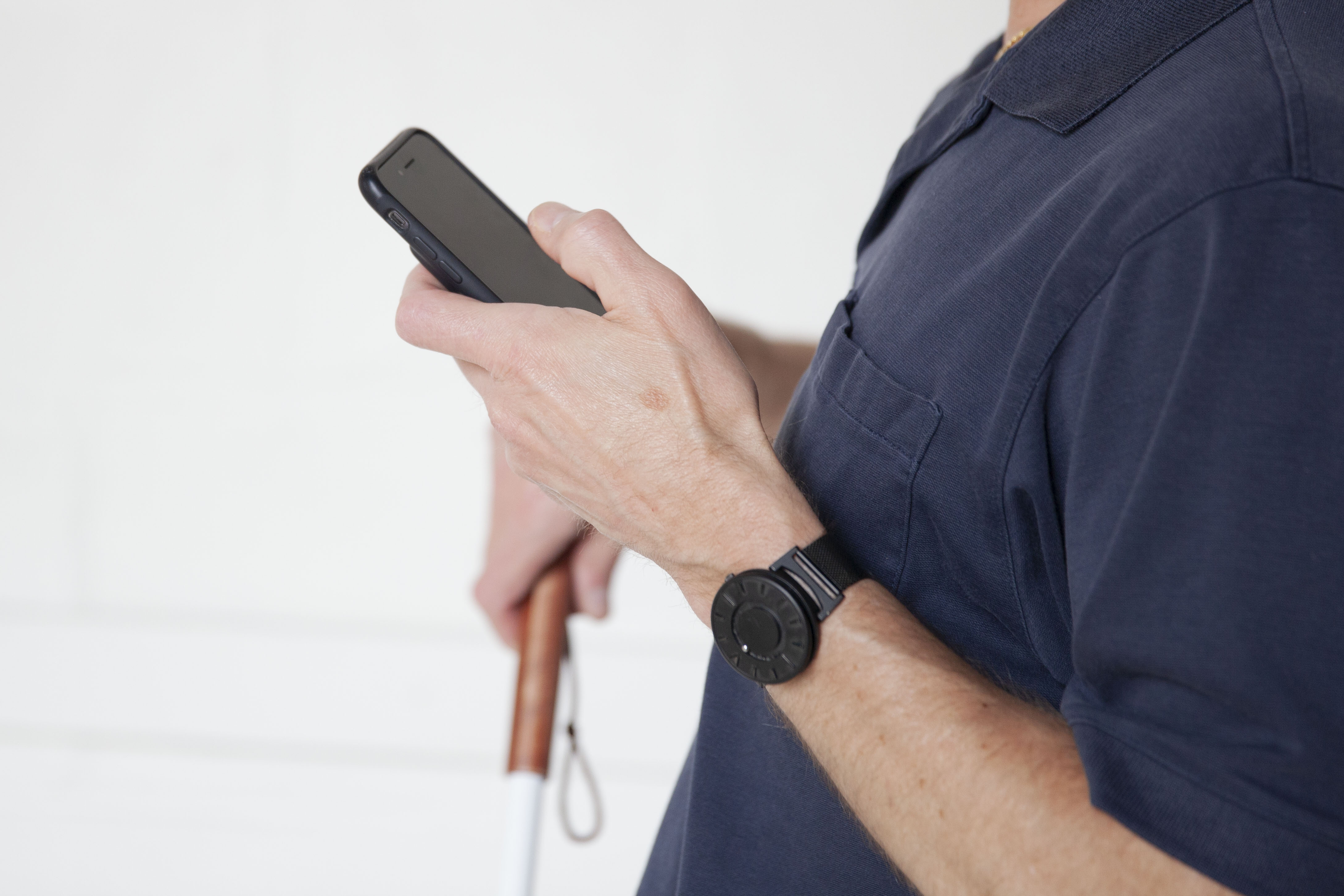 Man holding smartphone in one hand and white cane in the other