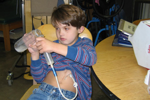 Dylan pouring liquid into bottle for tube feeding.