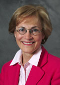 Head shot of Dr. Lylas G. Mogk. She is wearing a bight red suit and is smiling