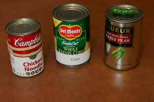 three canned foods with different markers including rubber band, large print label and magnet in the shape of a pea, which is the food in the can