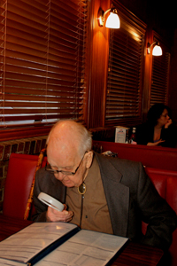 A man using a handheld magnifying device to assist with reading a menu