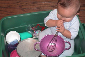 bebé en una tina de plástico con utensilios de cocina